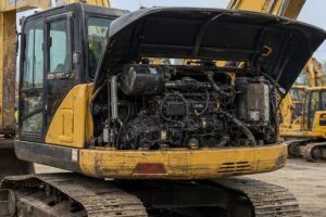 Used excavator engine bay open for yard inspection before import