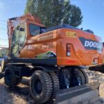 Rear view of the refurbished Doosan DX210W with wheeled undercarriage and blade